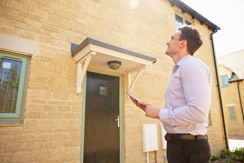 Feature image of How to Value a Property Male real estate agent looking up at a house exterior